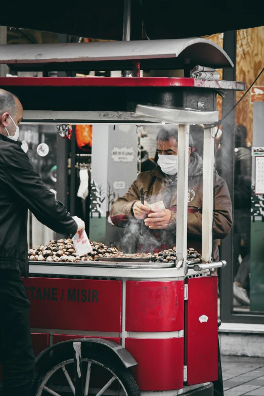 an old man standing in front of a food cart selling cookies