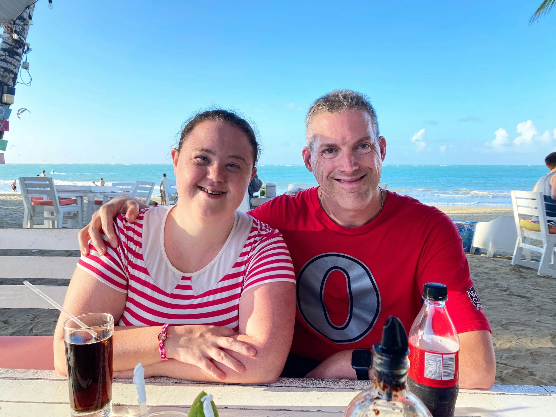 two people sitting next to each other on a beach