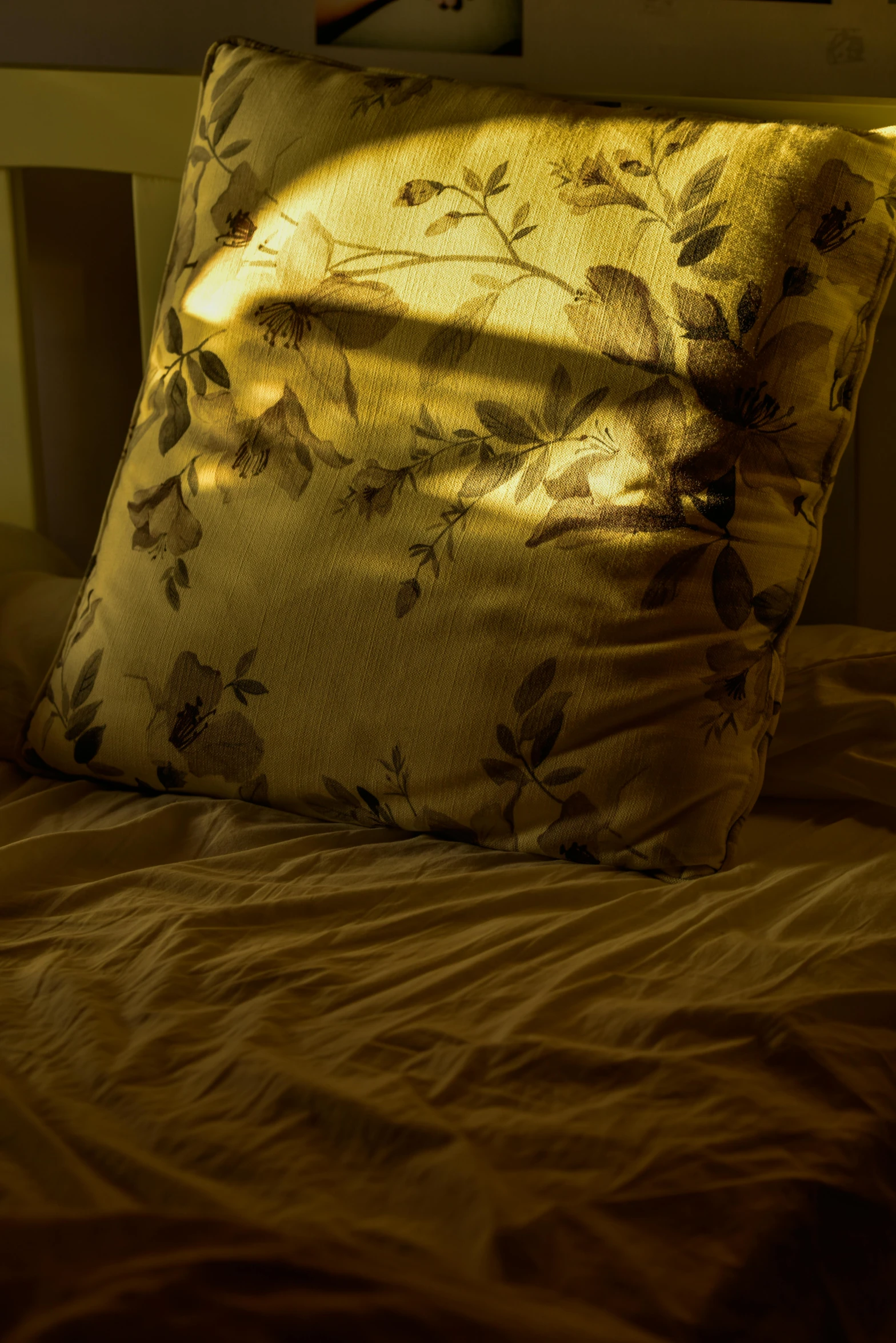 a square pillow laying on a bed next to pillows