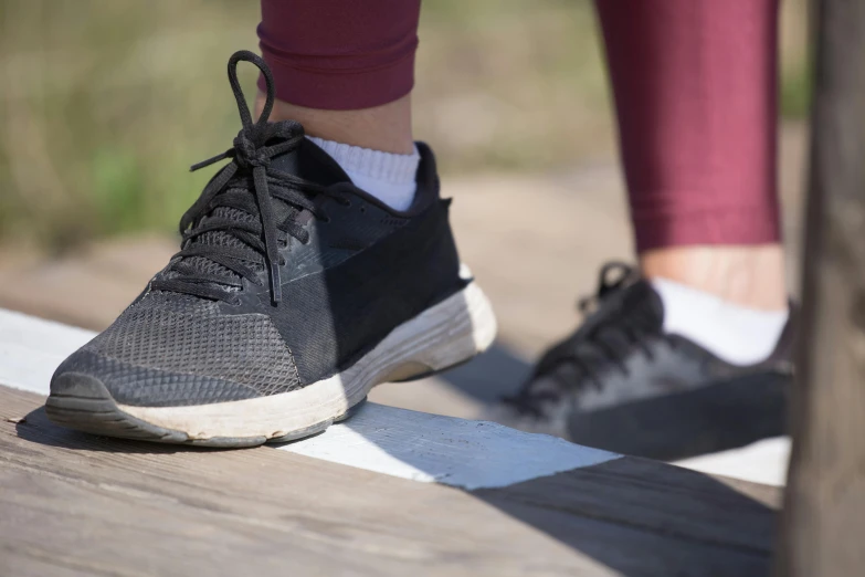 a woman in red and white sneakers walking across a bridge