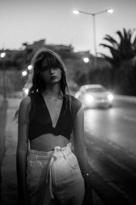 a woman in jeans and a crop top in the rain at night