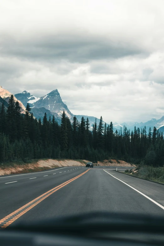 there is an empty road with mountains in the distance