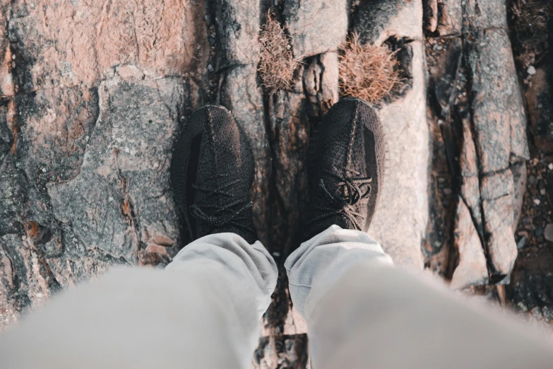 two feet standing on a cliff near some trees