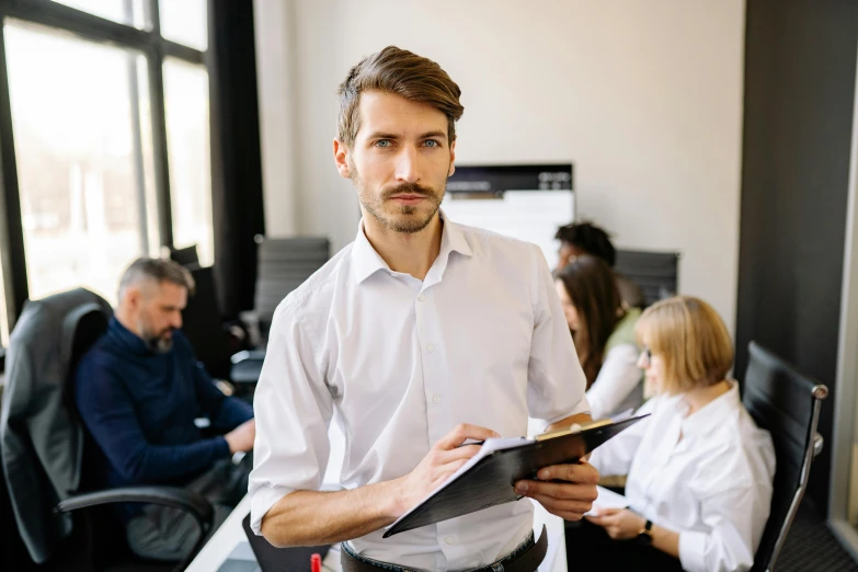 a young man holds papers in an office setting