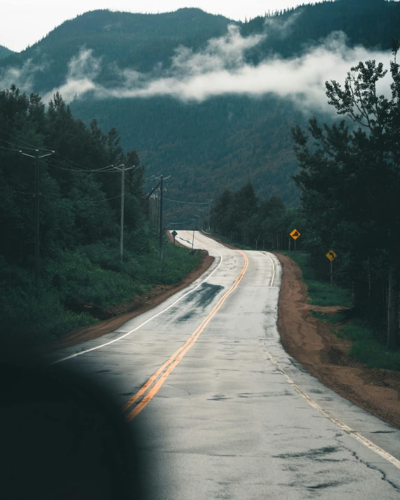 an empty road on the side of a hill surrounded by trees