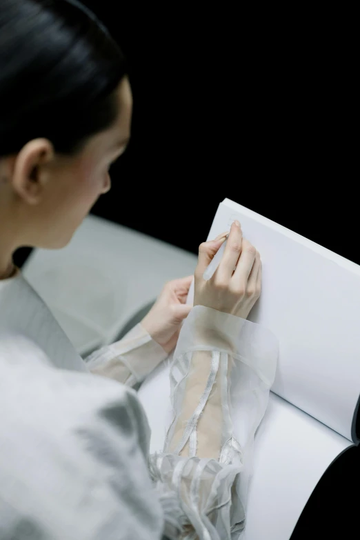 a woman wearing white is using a piece of paper