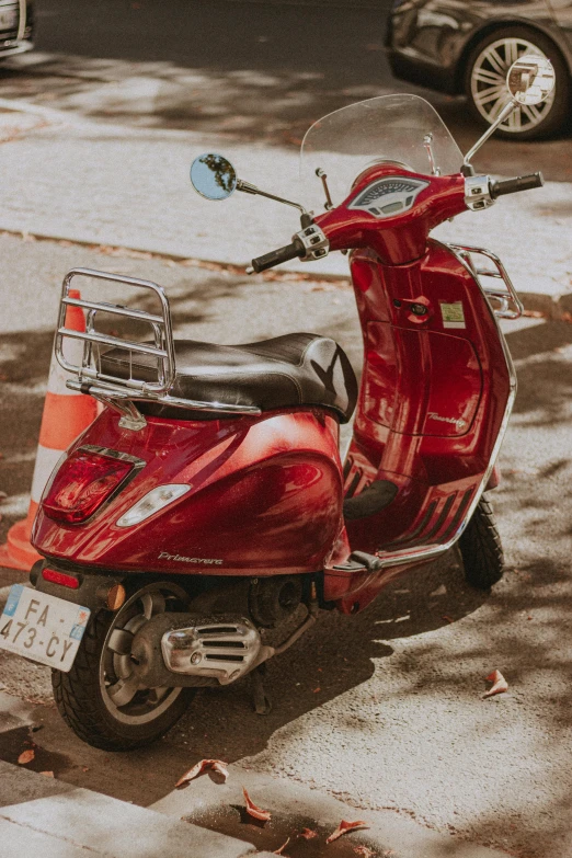 red scooter is parked near a curb on the street