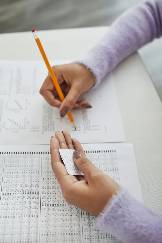 two people with pen and paper work on soing