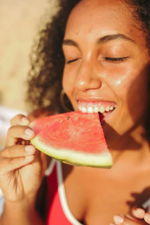 a young woman biting into a piece of watermelon