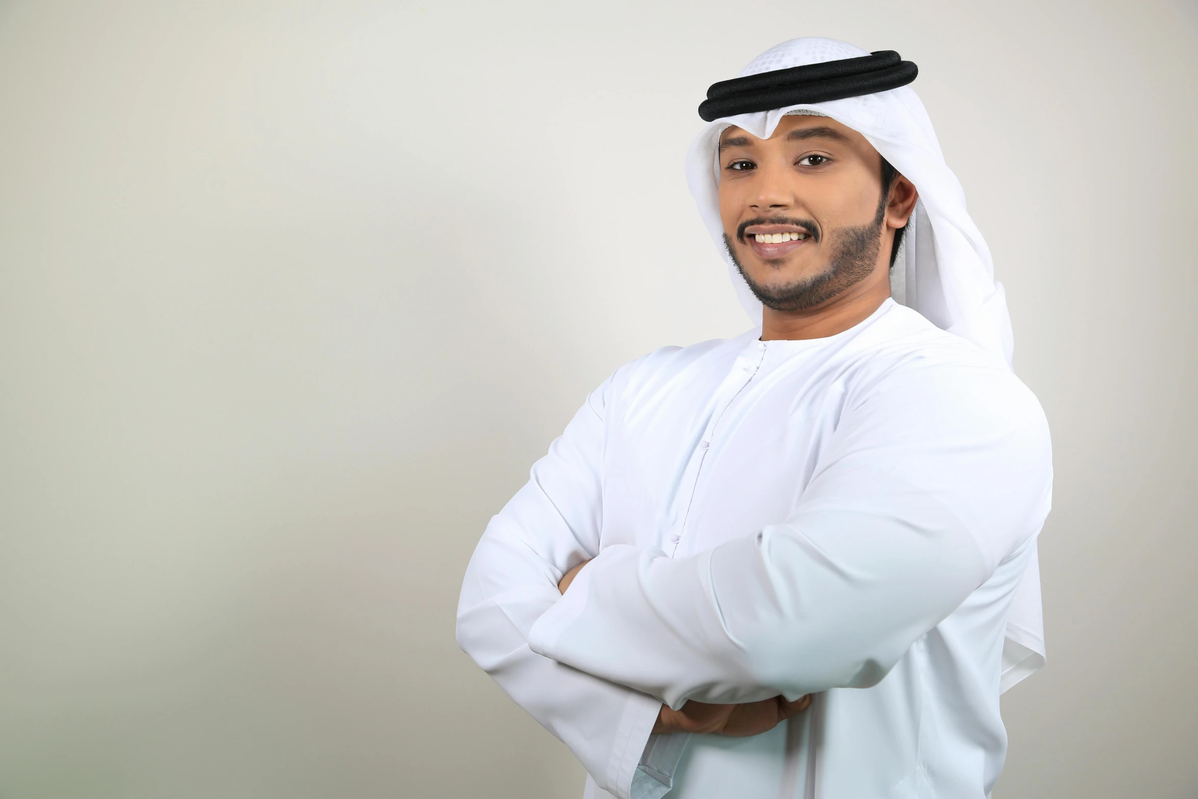 the man smiles in a head piece and is wearing a white outfit