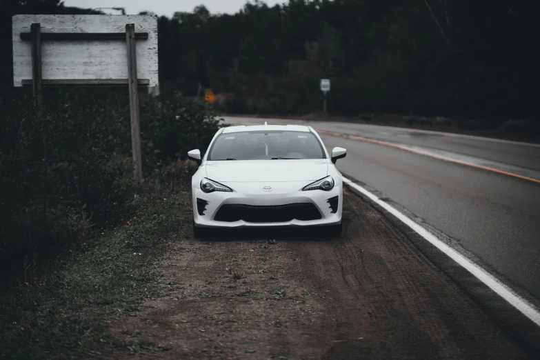 a white sports car parked on a narrow road