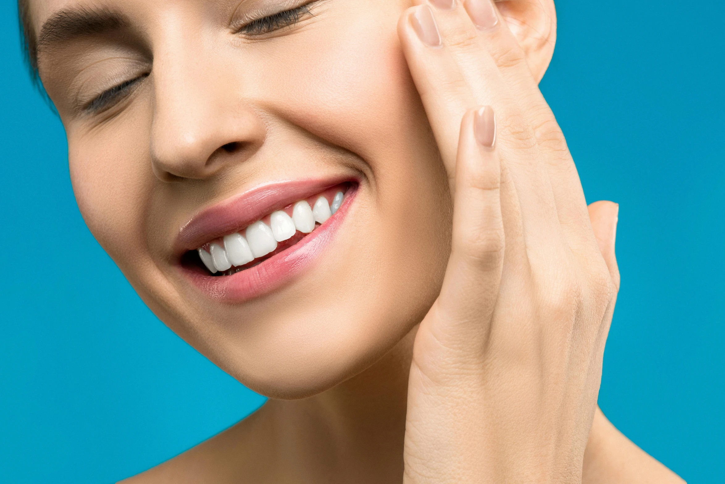 a woman smiles while touching her right ear