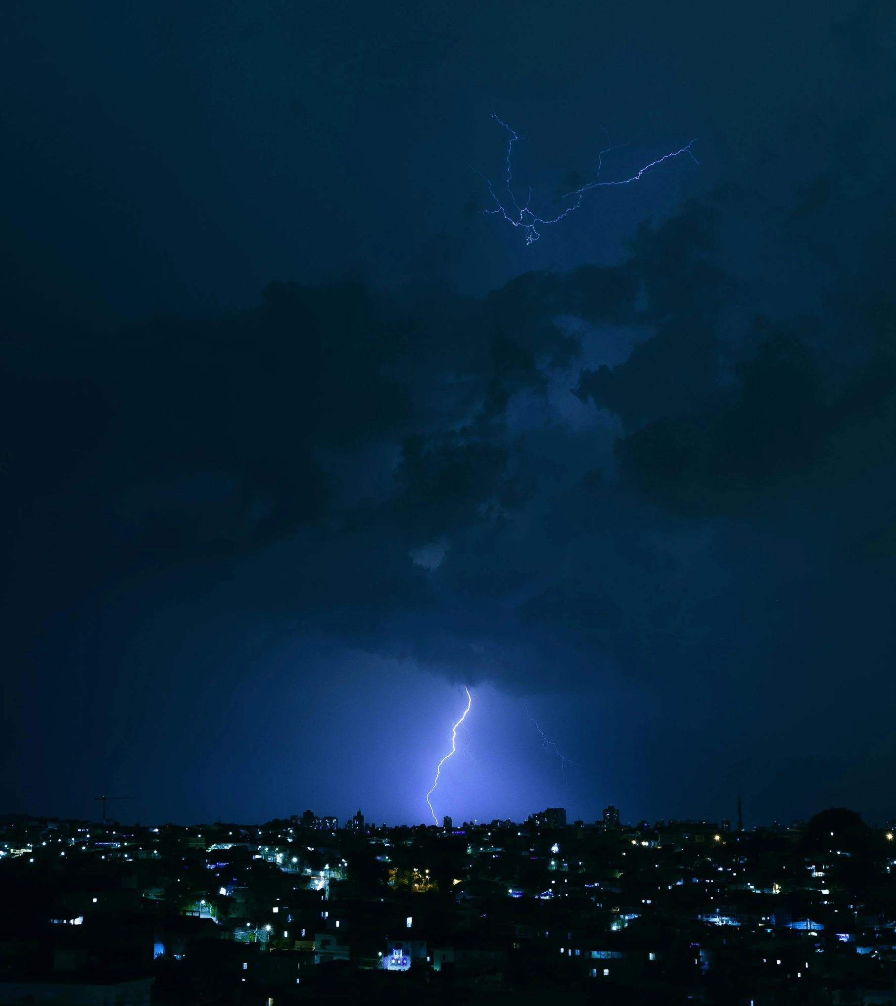 lightning strikes over the city lights are on the horizon