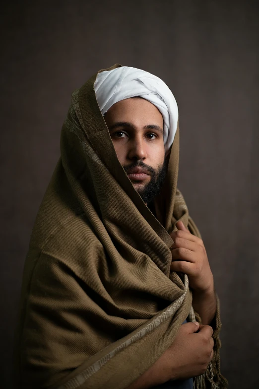 a man is wrapped in a cloth, looking intently at the camera