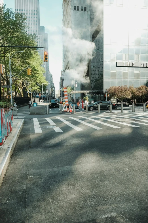 some smoke is coming from a building while cars and trucks are driving on the street