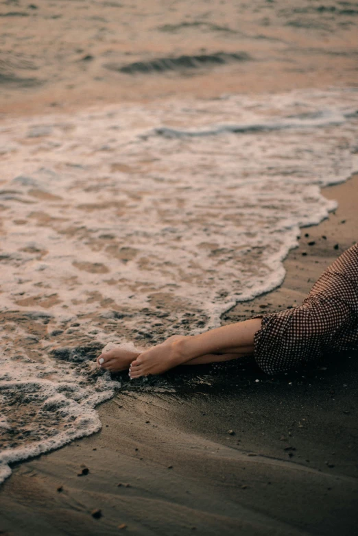 woman laying on beach next to waves in surf