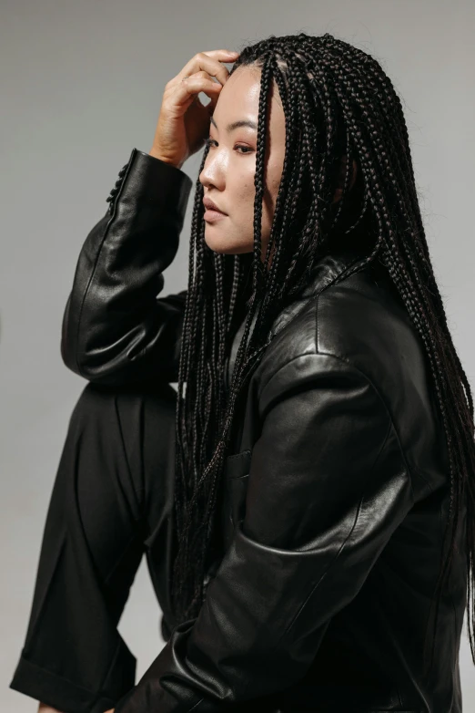 a woman wearing a black leather jacket with long twists on her hair