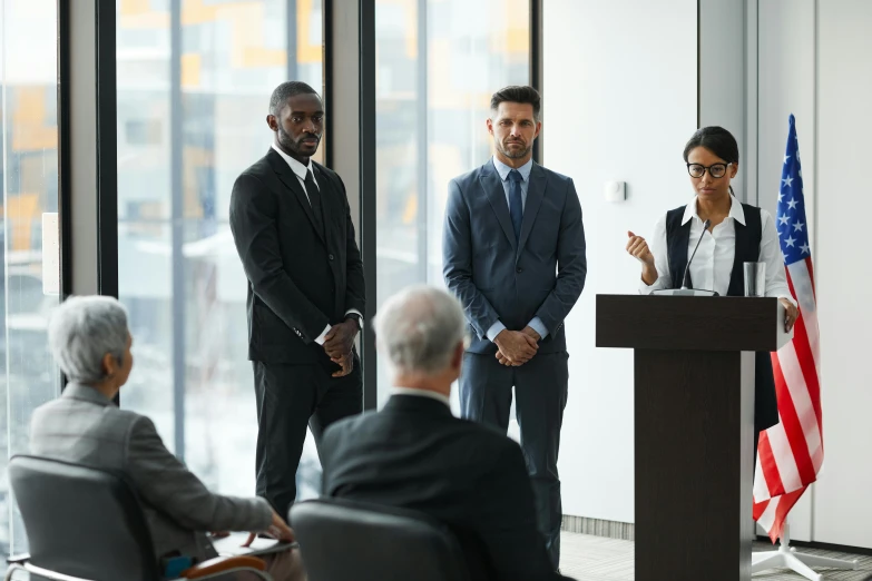 three business people stand at podium with american flags