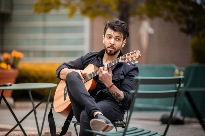 a man sits on a chair playing an acoustic guitar