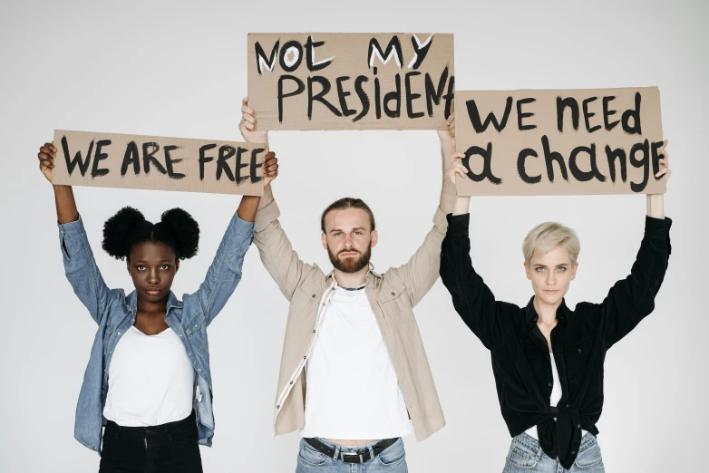 three people holding signs that read not my president, we need a change