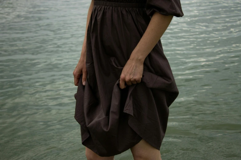 a woman standing in the water with her hands behind her back