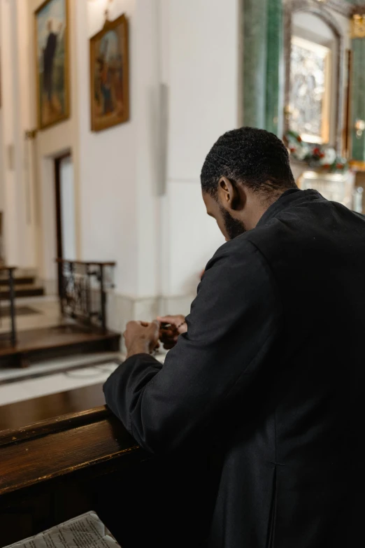 man in a black suit and a cross on his lap