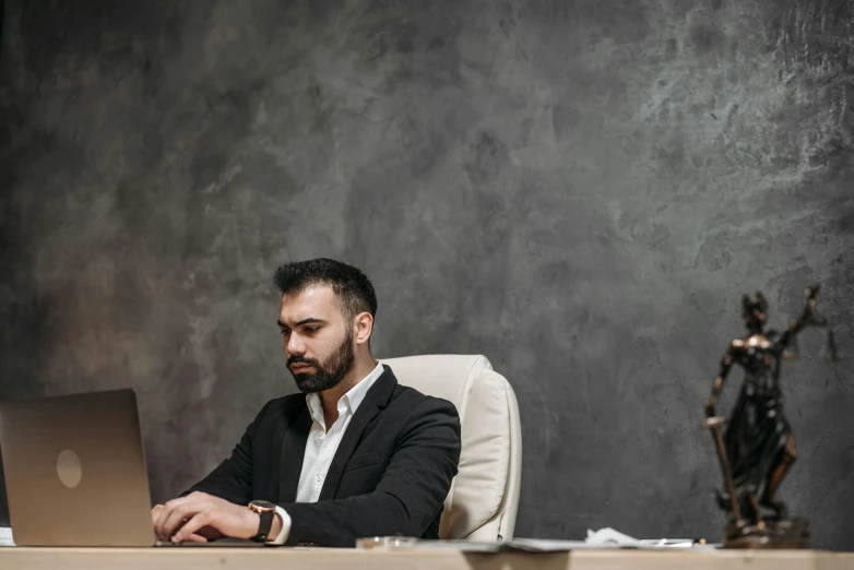 a man that is sitting at a desk with a laptop