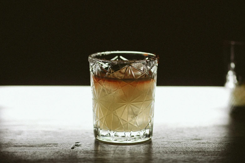 an old fashioned drink in a glass, a bottle is next to it