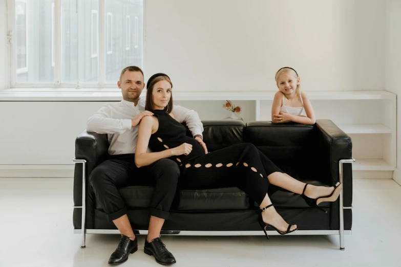 a man and woman sitting on a couch next to a small girl