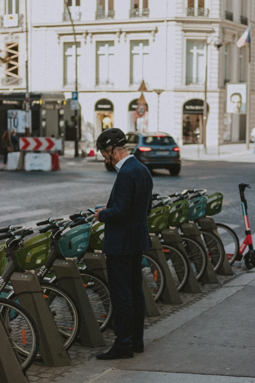 a man looking at his phone near some bicycles