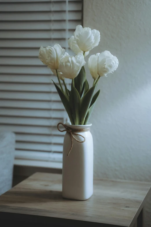 a bouquet of white flowers in a jar with a string