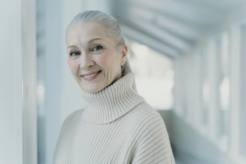 an old woman smiling wearing a turtleneck sweater