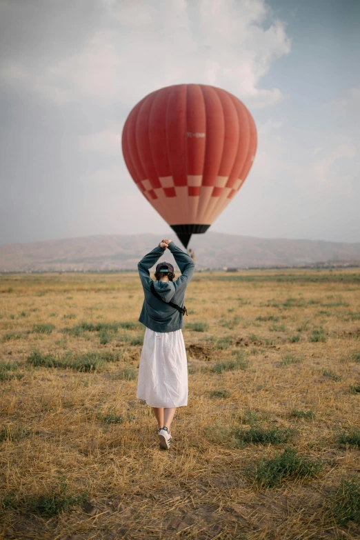 a person holding onto the side of a  air balloon