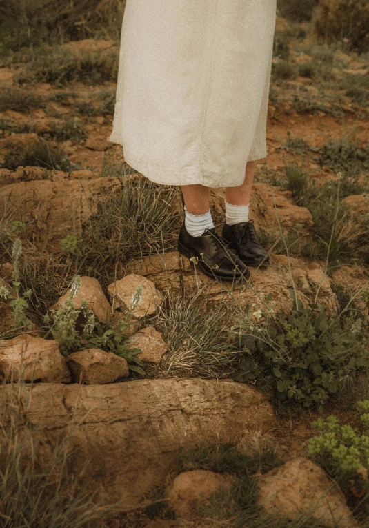 the young child stands near rocks and plants