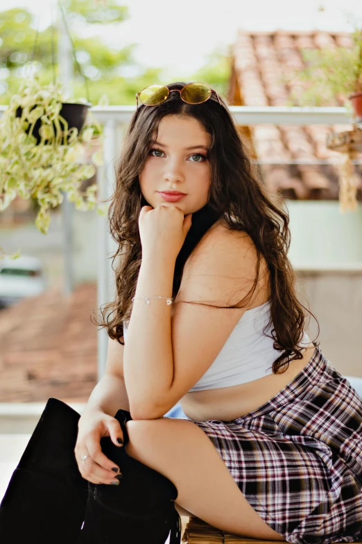 the girl poses in plaid shorts and a tank top