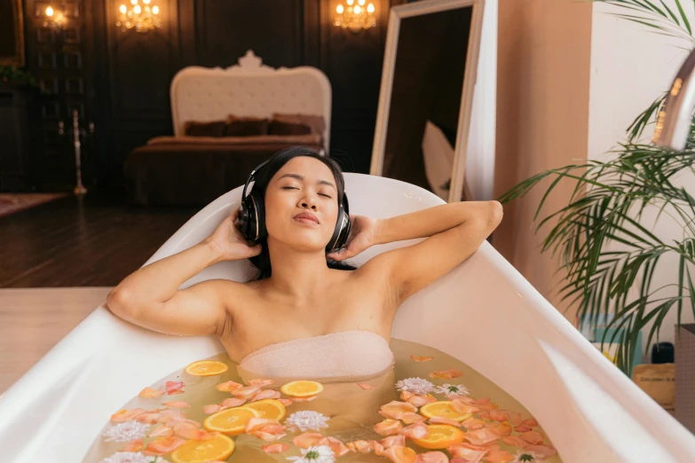 the woman with headphones is soaking in a bathtub