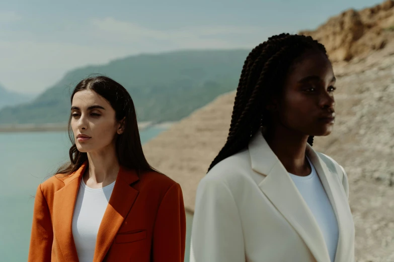 two women standing near a lake facing opposite directions