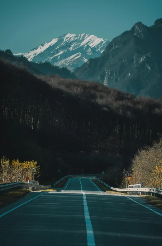 a paved road leads to a mountain range