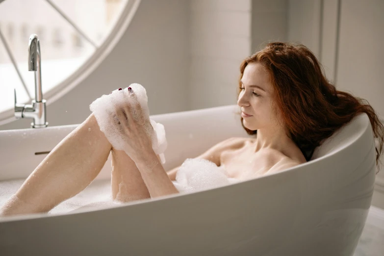 a woman in the bath tub has her legs propped up and her leg wrapped around the edge