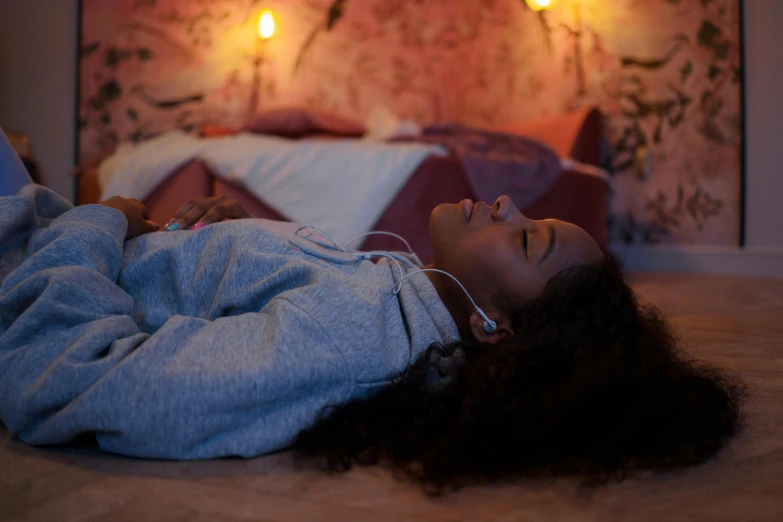 a young woman lying down on the ground with headphones in her ears