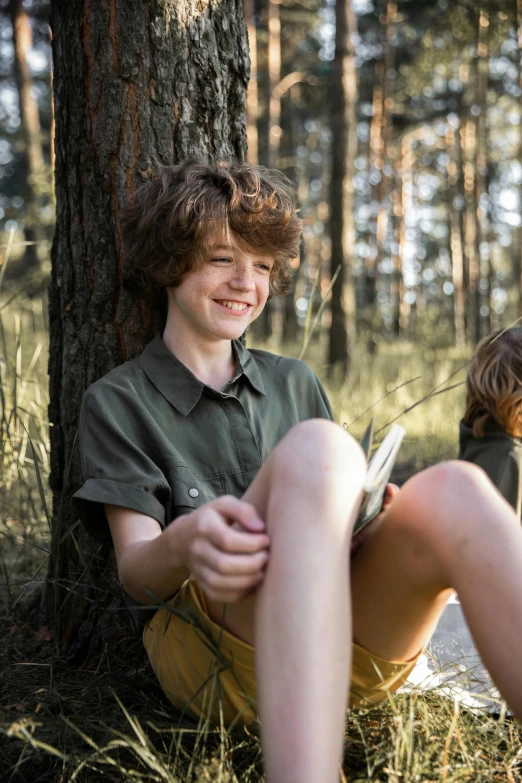 a boy smiles as he kneels in the woods