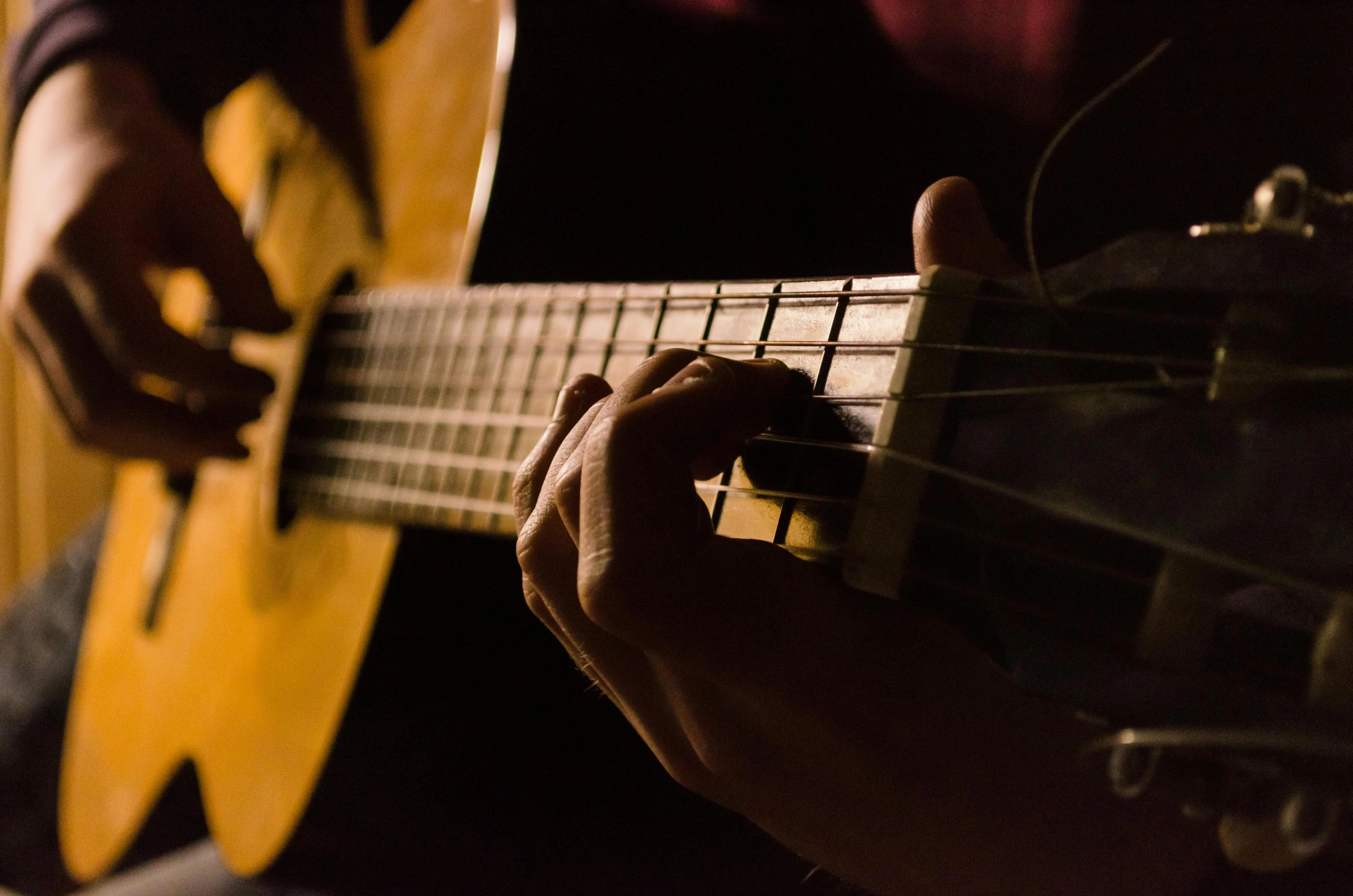 a person playing guitar in the dark with a blurred background