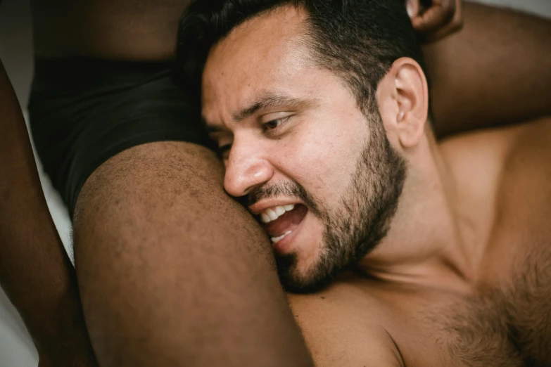 shirtless man in swimsuit laying  with a haircut