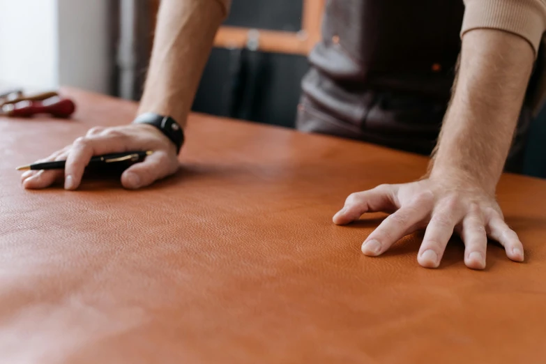 the person is holding a cellphone on a brown surface