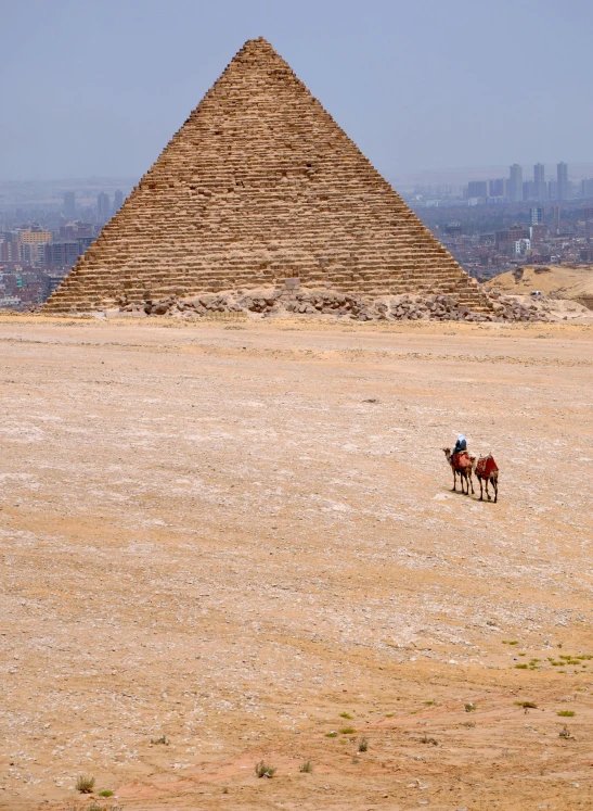 two men on horseback in front of a pyramid and a city