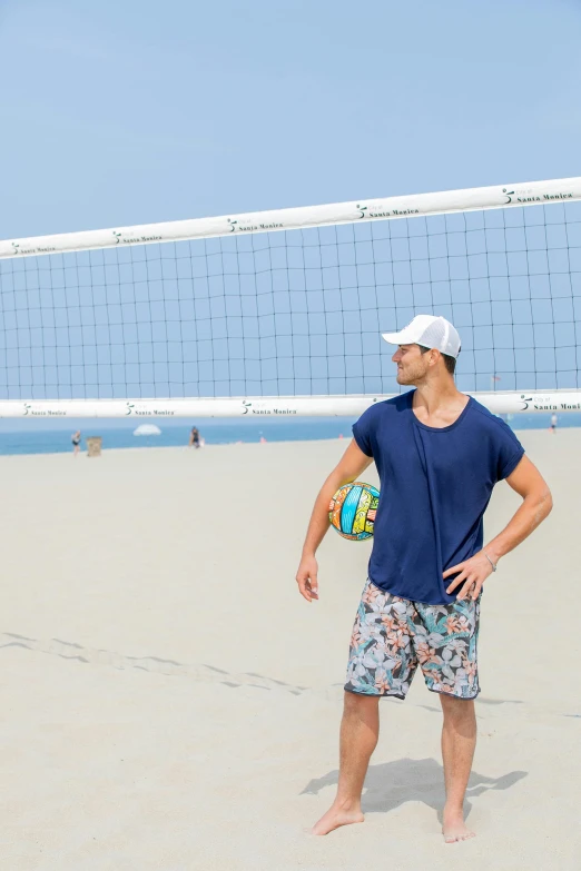 a guy standing in front of a volley ball on a beach