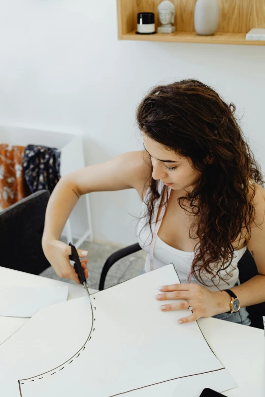 a woman in white top working on design with scissors