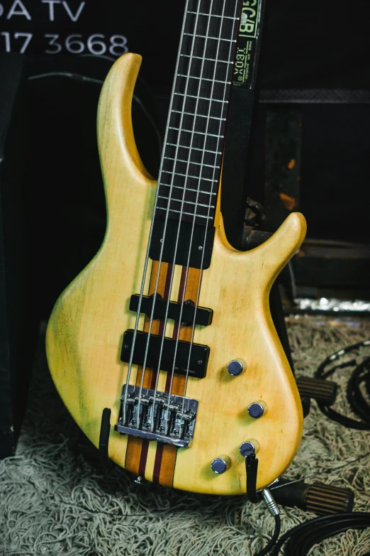 a yellow bass guitar is laying on a table