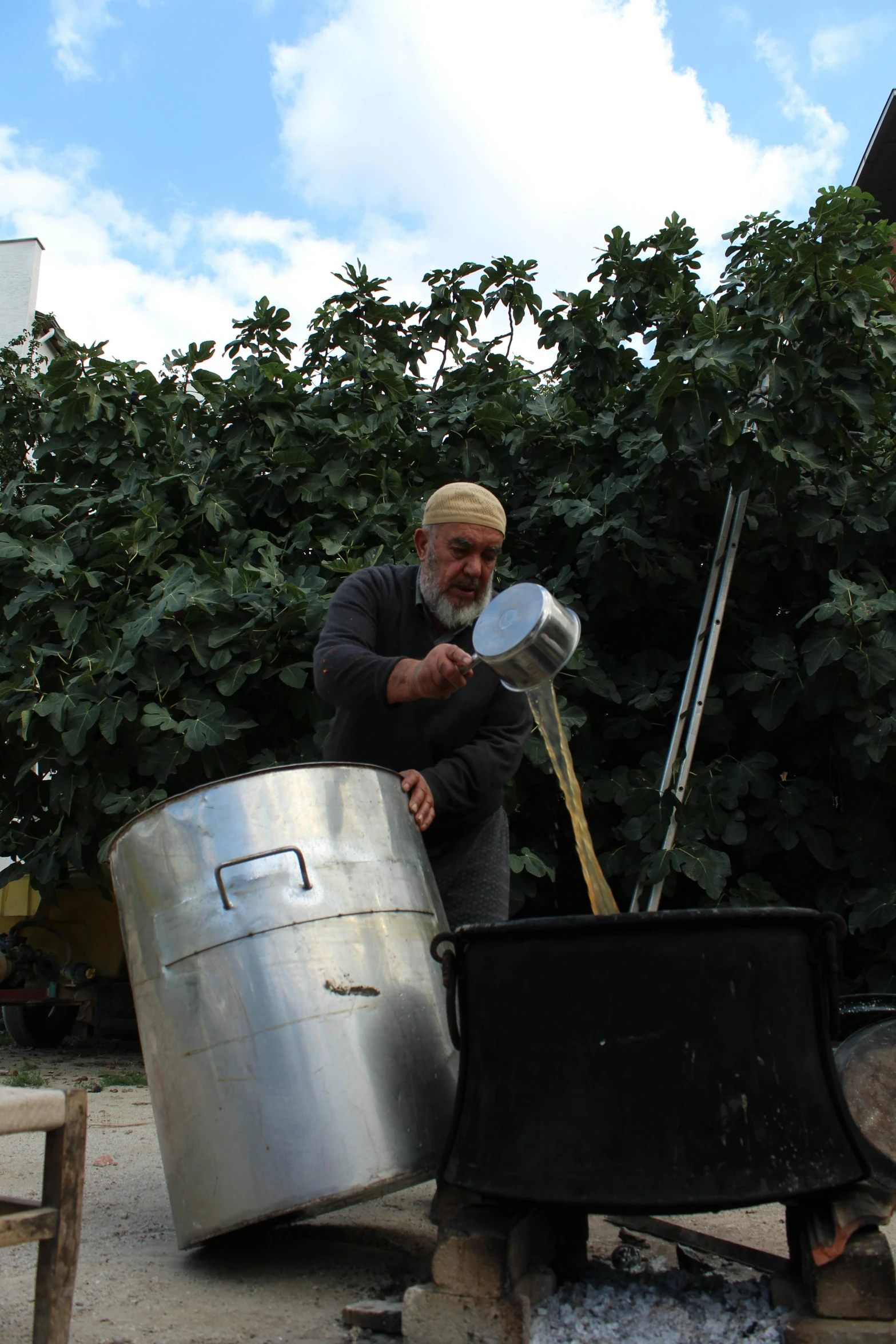 an old man preparing a pot in the firepit