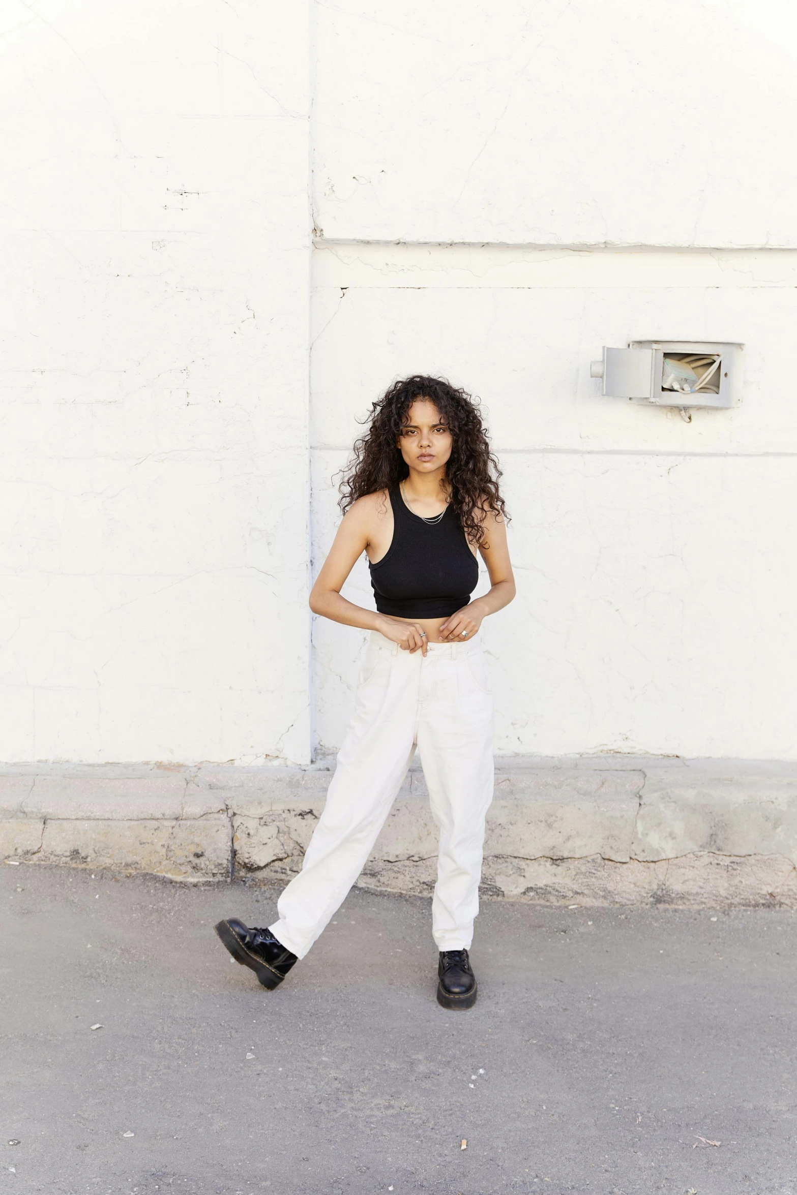 a woman posing for the camera with one foot in her pockets